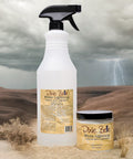 A spray bottle and a small jar labeled “Dixie Belle White Lightning Cleaner and Degreaser” sit on sand with dry plants, against a desert backdrop with dark clouds and a lightning bolt in the background.
