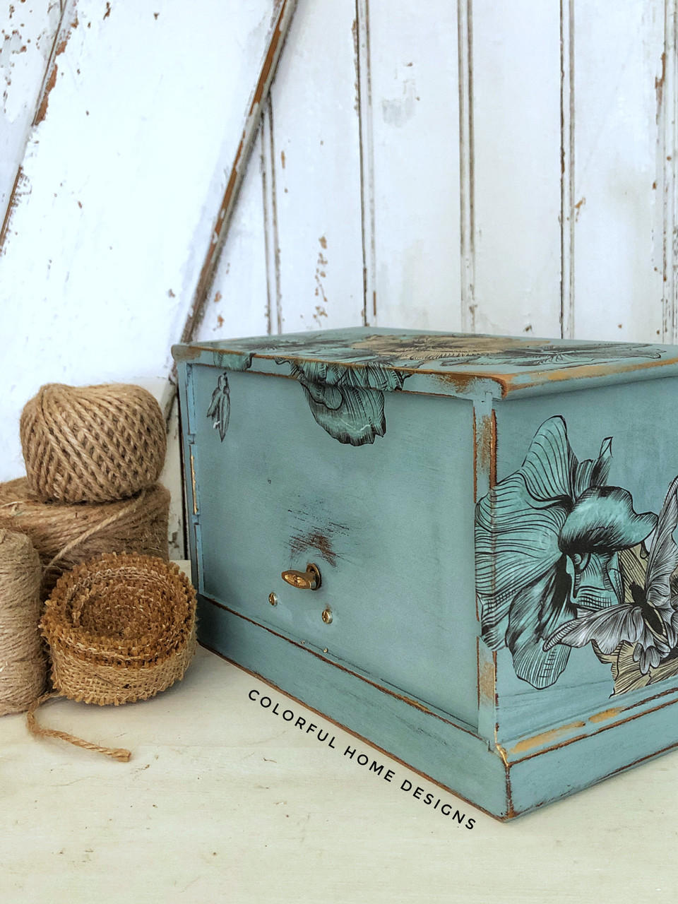 Belles and Whistles Blue and Yellow Floral - Rice Decoupage Paper is a simple way to visually enhance any surface of your project! Wooden box with Blue and Yellow Floral - Rice Decoupage Paper on top of the box spilling over the front of box, with some decoupage on the side. Staged with rolls of twine next to it.