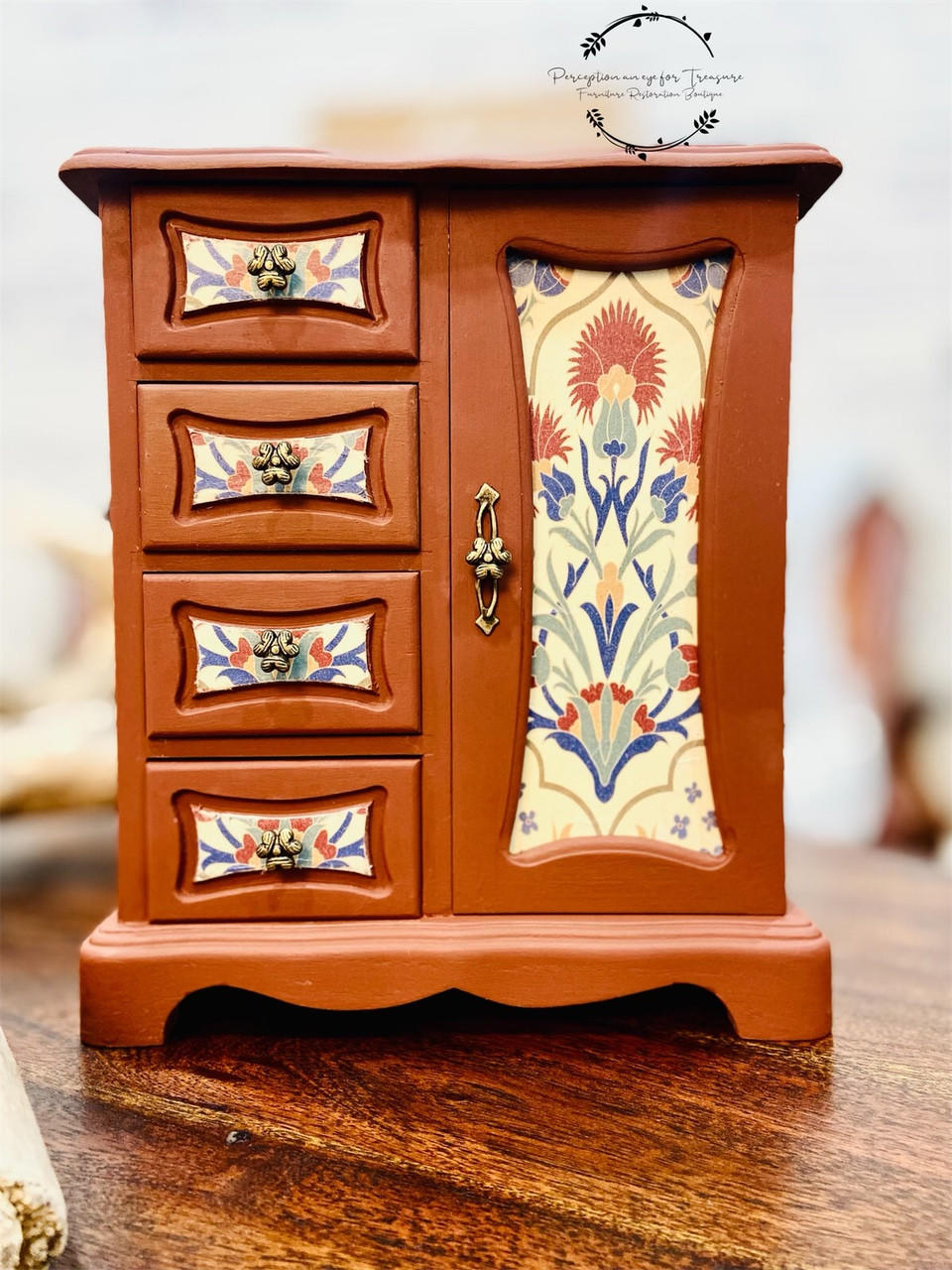 Belles and Whistles Whimsical Mediterranean - Rice Decoupage Paper is a simple way to visually enhance any surface of your project! A brown chalk painted jewelry box with bronze handles sits on a brown wooden table. The Whimsical Mediterranean Rice Decoupage Paper is applied to the front of the door and drawers, in the center.