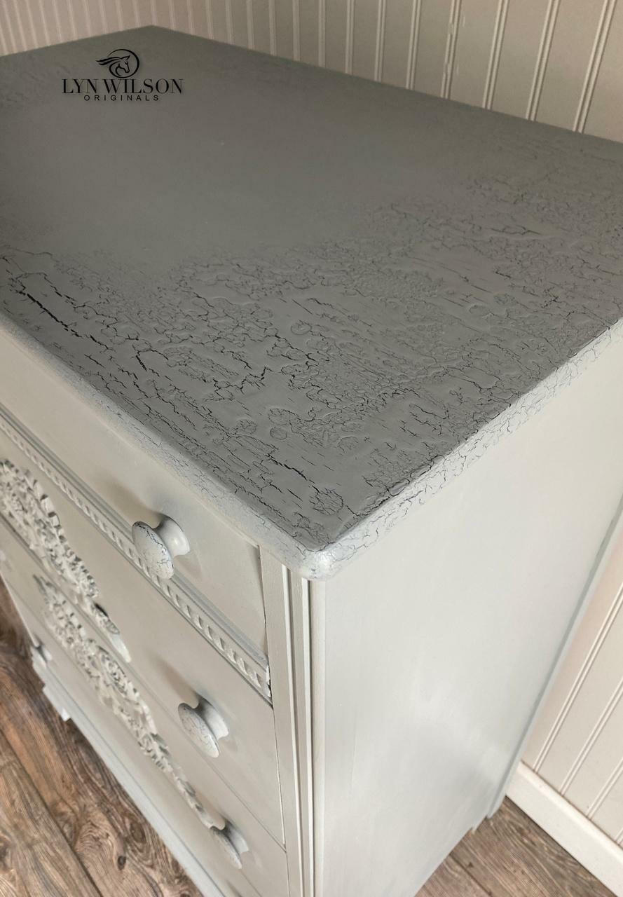 Dixie Belle Paint Crackle. A closeup of a white dresser with a gray top displaying the crackle effect on the top.