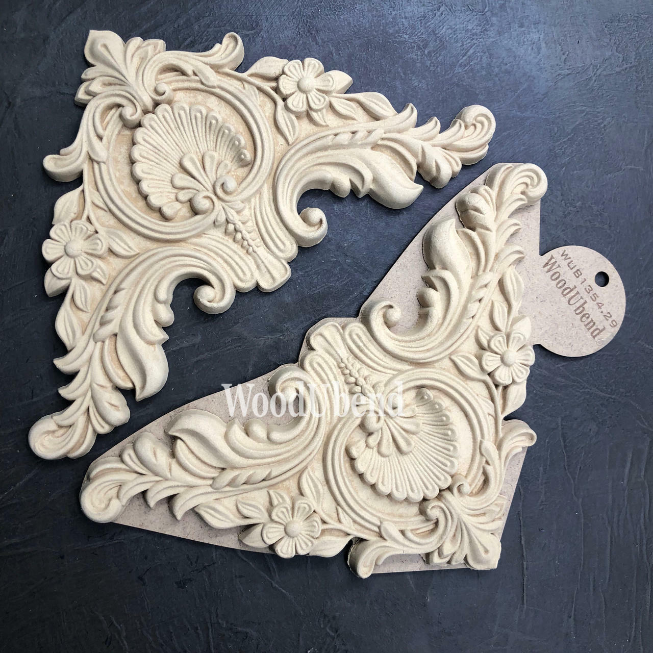 WoodUBend Corner Applique #1354.29 (Set of 2) is the perfect mouldable embellishment for any project!
This is a wood corner applique that can be secured to any piece of furniture. This applique had a fan in the center and two flowers on either side of the fan. It has a Victorian look with lots of "gingerbread" frills all over the corner applique. This picture shows the two that come in a pack. These appliques on resting on top of black leather.