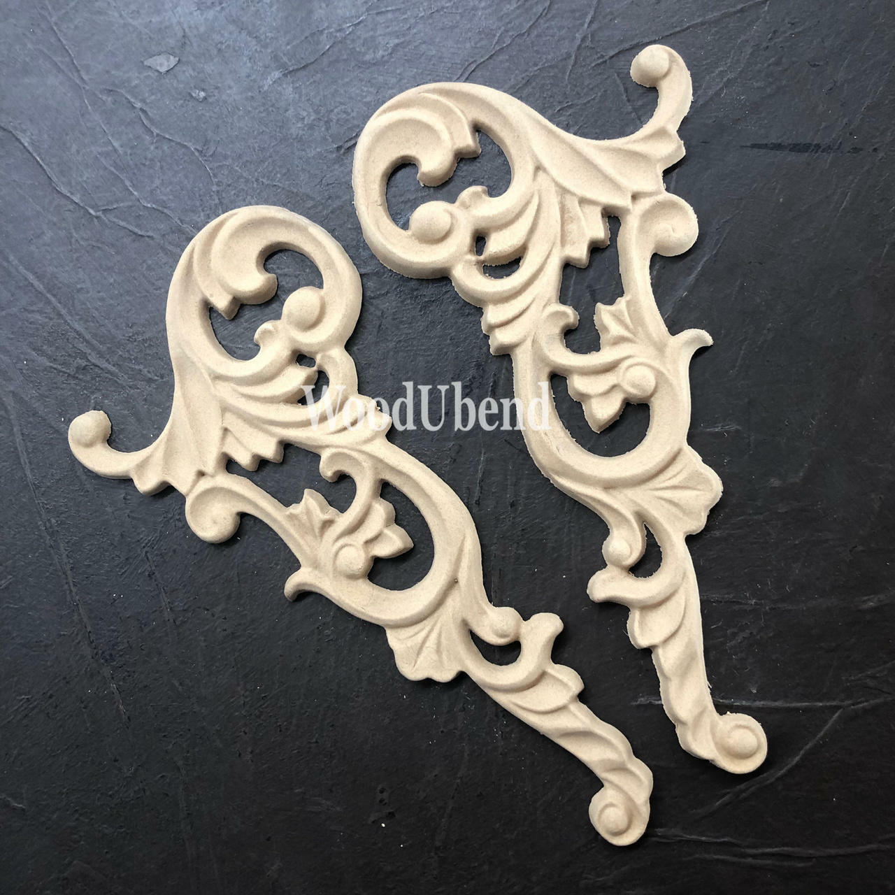 WoodUBend Corner Applique #2102 (set of 2) is the perfect mouldable embellishment for any project!
There are two wood-u-bend corner appliques, out of their packaging and resting on black leather. These are excellent to use for any FIY furniture project.