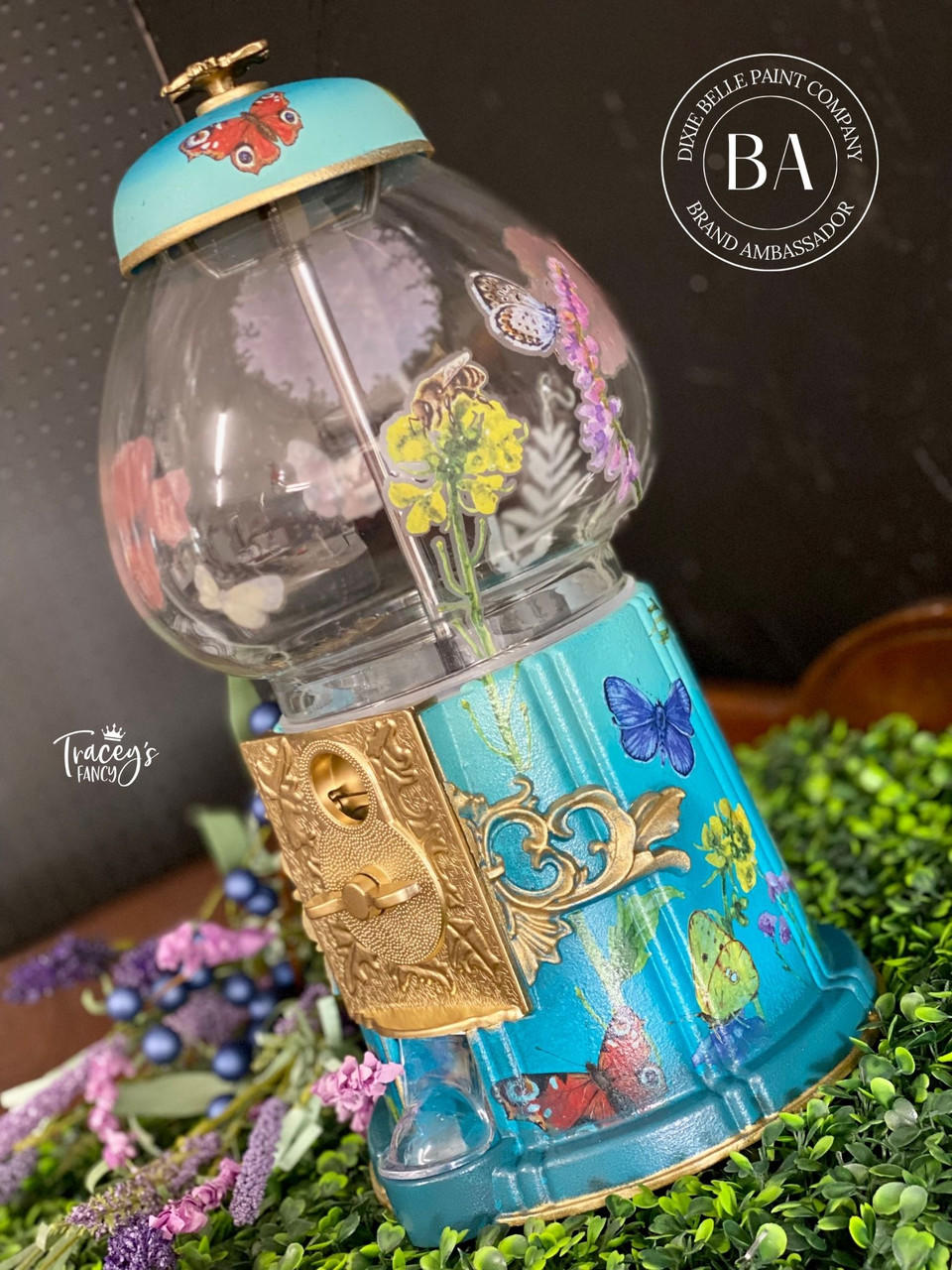 WoodUBend Fleur-de-lis Applique #2092 (set of 2)
Here is an empty gumball machine resting on faux evergreen. It has a Fleur-de-lis applique on the base and butterfly decoupage. it is staged with dried blueberries and flowers.