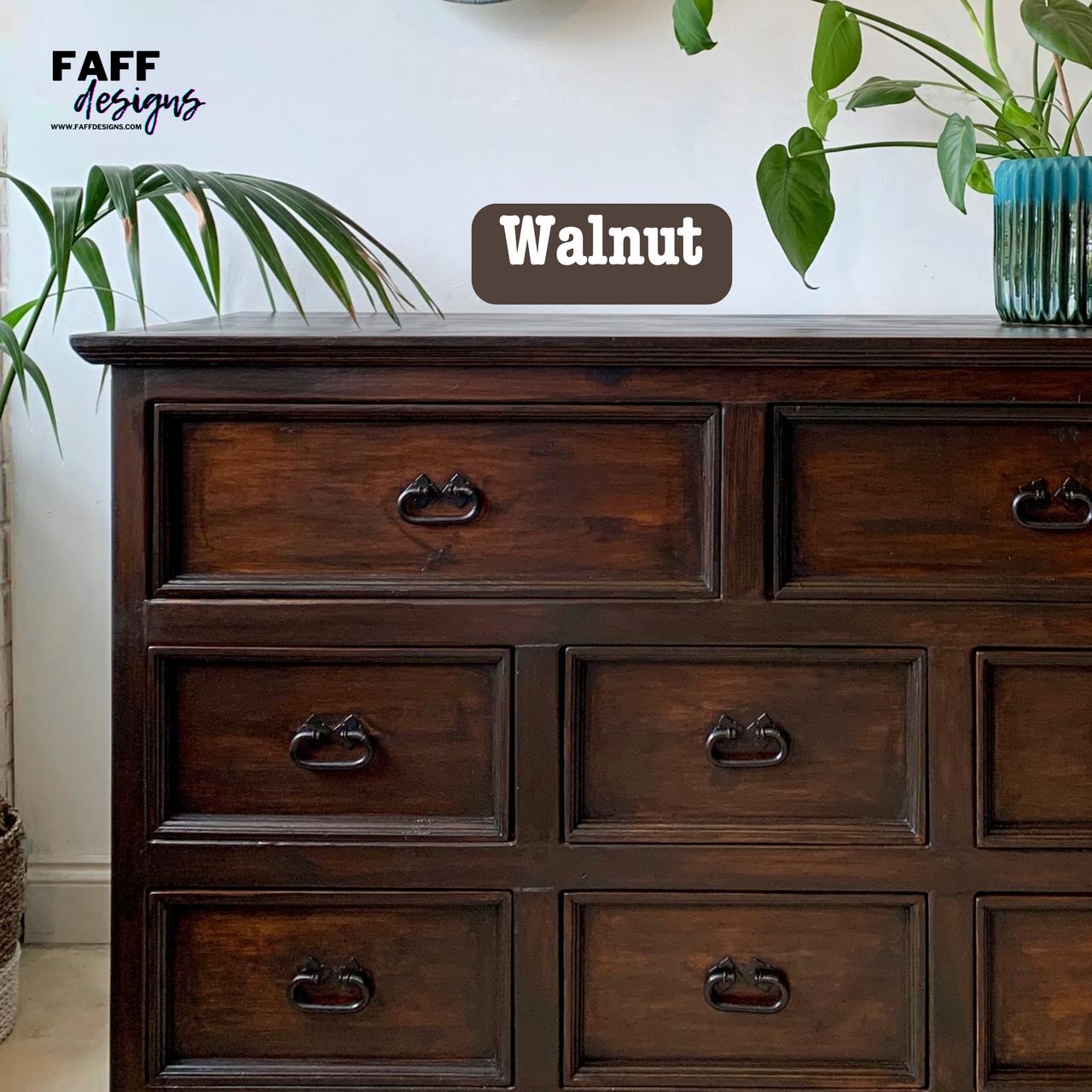 Dark wooden dresser with eight visible drawers, featuring metal handles. A label reading "Walnut" is visible. Potted plants are positioned on and beside the dresser. The text "FAFF designs" is in the top left corner.