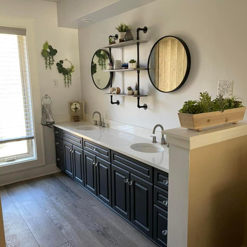 Bathroom with two sinks, marble counter tops, the cabinets have been painted with Silk All In One Mineral Paint.  Two round mirrors and plants are staged throughout.