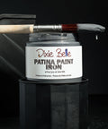 Dixie Belle Patina Paint Iron with a brush on a dark background