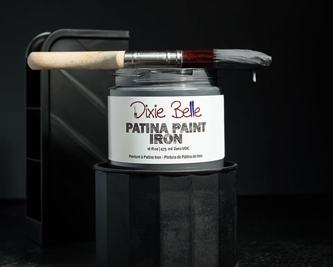 Dixie Belle Patina Paint Iron with a brush on a dark background
