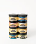 Eight jars of Dixie Belle Moonshine Metallics paint are stacked in two columns. Each jar has a black lid and a yellow label, with different colors visible through the containers.