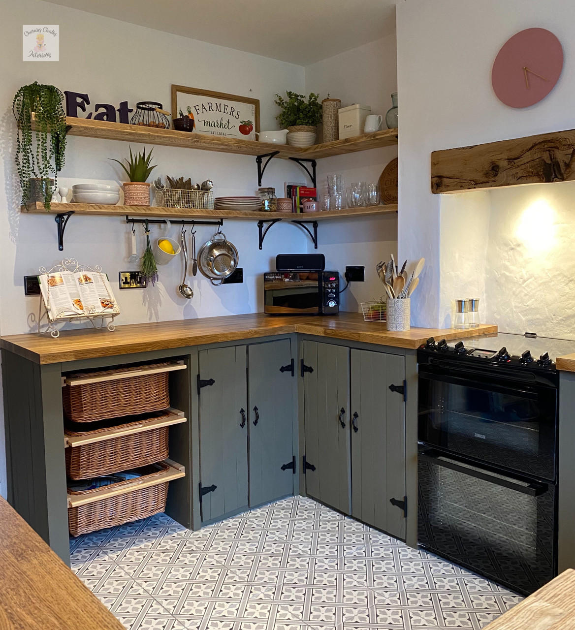 Photo of a painted kitchen with Silk All In One Mineral paint in the color, color is Hampton Olive, this piece painted by Cherubs Chalks Interiors. Staged with baskets, recipee books plants, shelving with class and plates and utensils