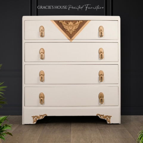 White dresser with gold accents and decorative elements on a dark background