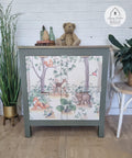 Belles and Whistles Woodland Nursery - A1 Rice Decoupage Paper.  Small side table with Woodland Decoupage Rice paper applied staged with teddy bear and books and bottles on top and a plant in gold vase on left side and chair with plant on right side