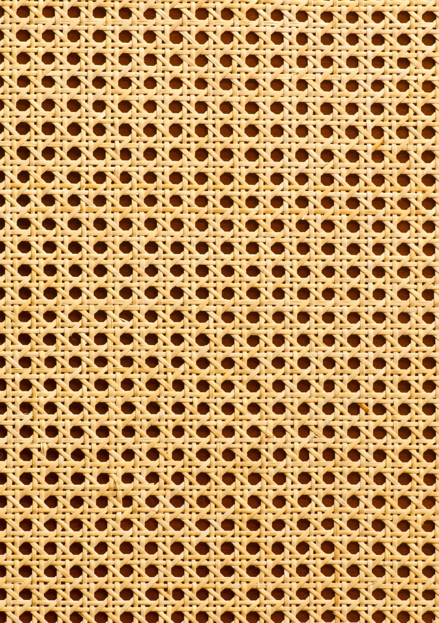 Close-up of a woven cane chair seat with a hexagonal pattern. The natural beige material forms a symmetrical, openwork design, creating a textured and airy appearance.