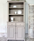 Beige painted hutch makeover. Staged with white plates and cups inside the open cabinets.
