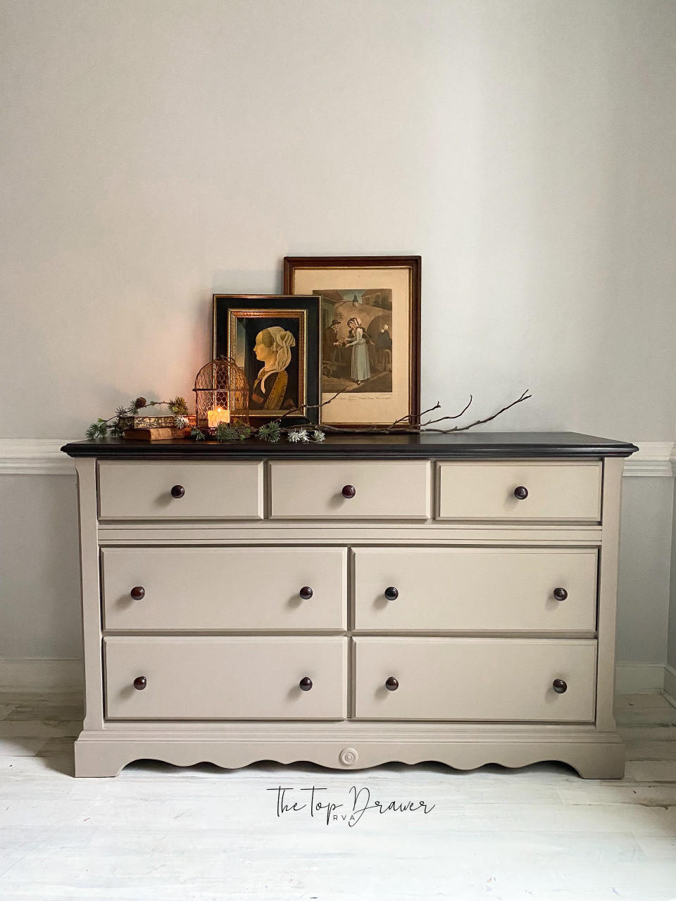 Beige painted dresser makeover with black knobs and a black top. Staged with sticks and pictures on top.