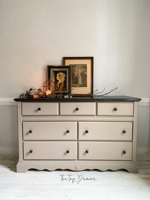 Beige painted dresser makeover with black knobs and a black top. Staged with sticks and pictures on top.