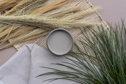 Overhead shot of an open jar of Badlands staged on a burlap table runner with faux greenery and a drop cloth.