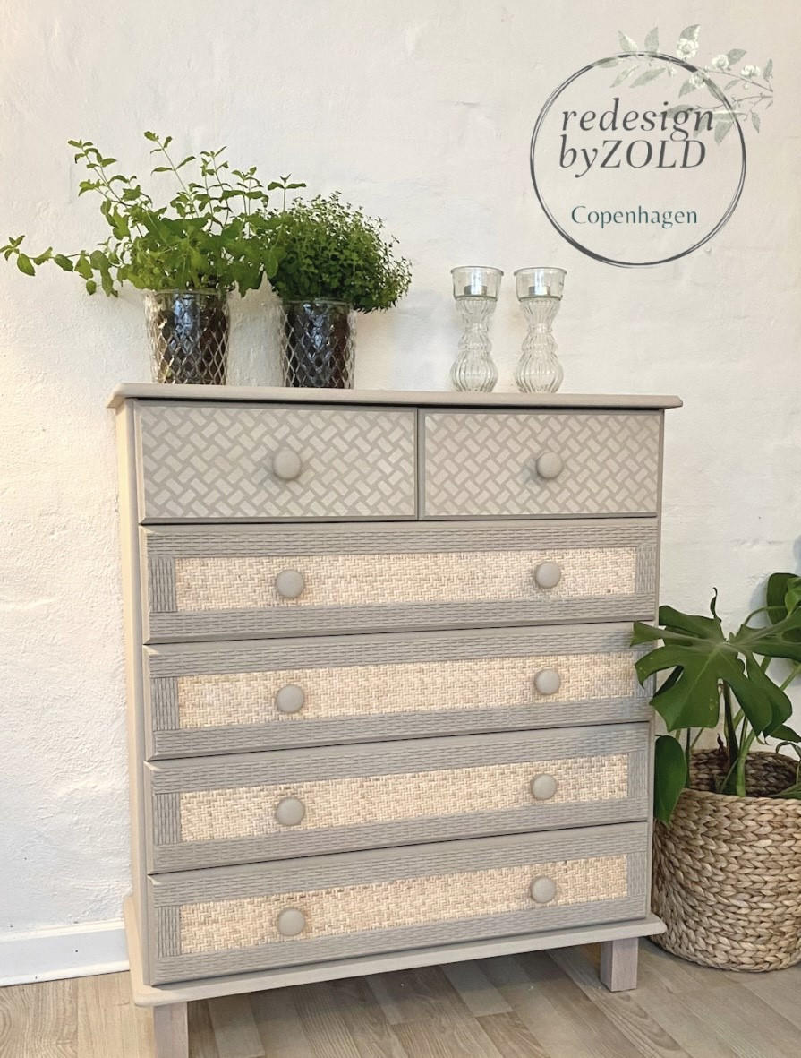 Belles and Whistles Basket Weave - Stencil, A Basket Weave design on our Premium Mylar Stencils feature a high grade material allowing for the most precise stenciling techniques and applications. Our stencils can be used on walls, furniture and more. Durable and reusable.  Laser cut on 1o mil Mylar.
Image of tall tan dresser with 2 drawers with Basket Weave - Stencil at the top and 4 bottom rattan drawers. Staged with two Glass planters with greenery and two empty glass candle holders.