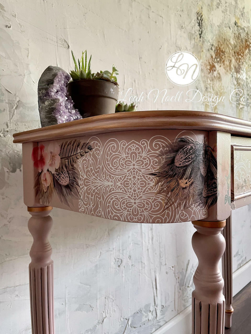 Belles and Whistles Delicate Lace - Silkscreen Stencil provides an extra decorative touch to any project!
This is a hall table with long legs.  It's painted in a brown tone and has Delicate Lace stenciling on the side of the table.  There is also flowers ad pinecone decoupage on the side of the table.  There is a purple geode and two flower pots on top of the table.