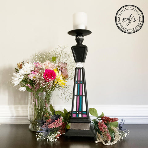 Belles and Whistles Dixie Shine 
Tall black Candle holder with Dixie shine accenting the body piece. Staged with bundles of flowers on each side of candle and a glass vase with a bundle of flowers on the left side.