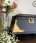 Belles and Whistles Dixie Shine 
Antique black jewelry box  with Gold Dixie Shine in the corners and hardware to give it a chic look. Furniture makeover staged next to wide flower vase with wildflowers inside.