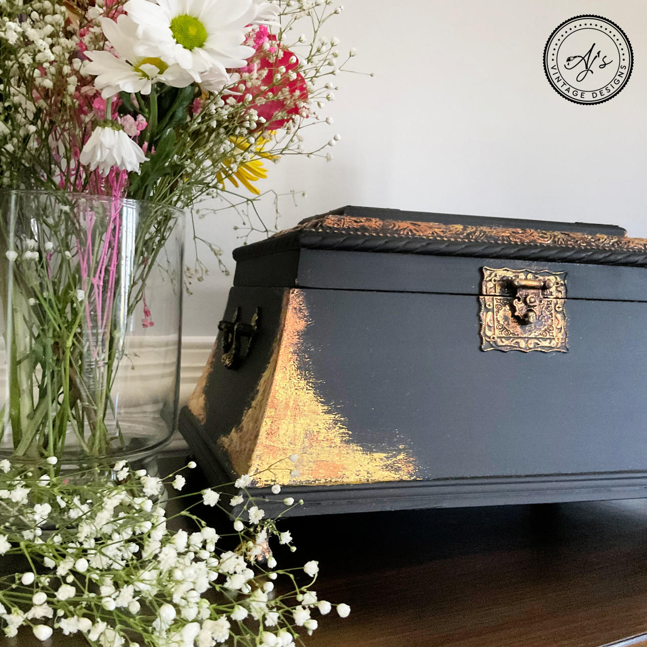 Belles and Whistles Dixie Shine 
Antique black jewelry box  with Gold Dixie Shine in the corners and hardware to give it a chic look. Furniture makeover staged next to wide flower vase with wildflowers inside.