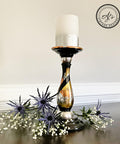 Belles and Whistles Dixie Shine 
Candle holder with a silver metal base using all 3 Dixie shine color around base with a black swirl from top to bottom of piece. Staged with a white with silver gradient candle and purple and white flowers are the bottom.
