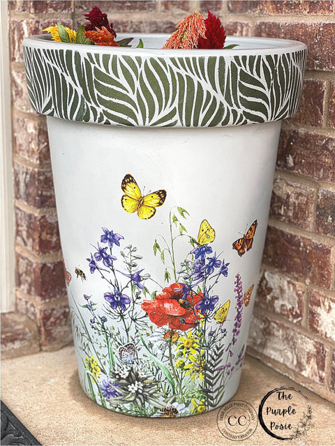 Belles and Whistles Enchanted Garden - Stencil provides an extra decorative touch to any project! White painted pot with the Wildflowers & Butterflies rub on furniture transfer applied to the base and body. Enchanted Garden Stencil applied on the rim of the pot in Deep Woods Moonshine Metallics paint.