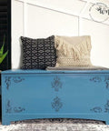 Belles and Whistles Floral - Silkscreen Stencil provides an extra decorative touch to your project!
A blue chest with the Floral - Silkscreen Stencil on the front panel staged with a white and black decorative pillows.