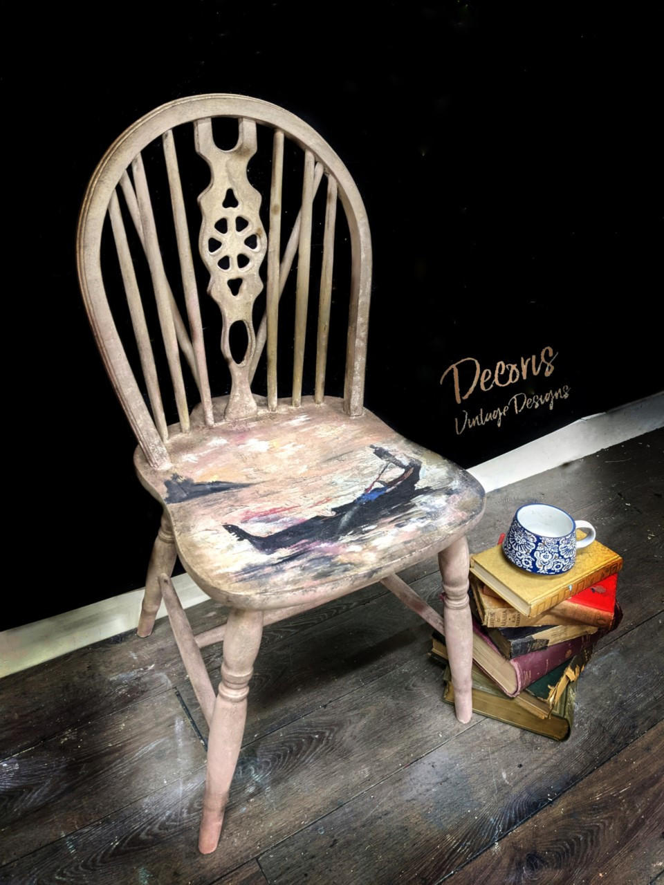 Belles and Whistles Gondola and Landscape - A1 Rice Decoupage Paper is a simple way to visually enhance any surface of your project! White stained wood chair with Gondola and Landscape - A1 Rice Decoupage Paper in center of the seat. Staged on wood floor and black background and a pile of books next to chair with blue and white mug on top of books.