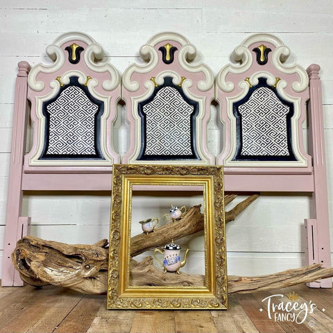 Belles and Whistles Greek Key - Stencil provides an extra decorative touch to any project! Pink headboard with white woodwork and gold with black accents on inner woodwork. Contains Greek Key - Stencil in center pieces of furniture. Staged with an empty gold frame a large driftwood branch and three pink teapot set in the center of said frame.