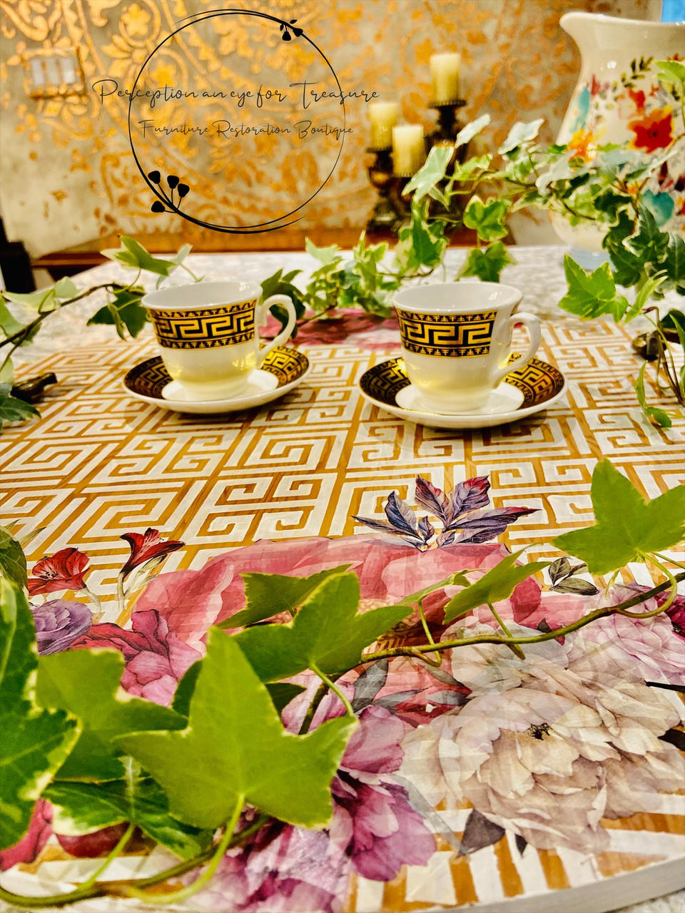 Belles and Whistles Greek Key - Stencil provides an extra decorative touch to any project! A white table with Greek Key - Stencil in gold all on top with Vintage Floral- Transfer on opposite sides of table. Staged with greenery surrounding table with two tea cups with similar patterns as Greek Key - Stencil in the center.