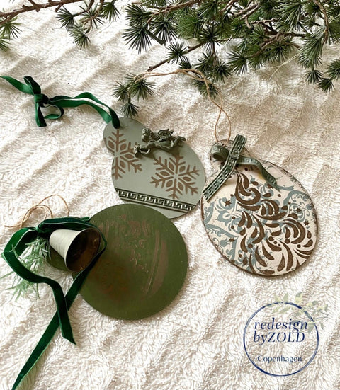Belles and Whistles Holiday Joy - Stencil provides an extra decorative touch to any project!
Wooden christmas ornaments with Holiday Joy Stencil staged on a white cloth and in the corner you see pine branches.