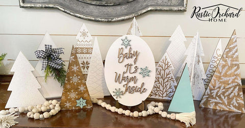 Belles and Whistles Holiday Joy - Stencil provides an extra decorative touch to any project!
Wooden mini christmas trees all white or tan with Holiday Joy Stencil on all of them with a sing in the middle everything that says " BABY IT'S WARM INSIDE".