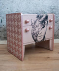Belles and Whistles Houndstooth - Stencil provides an extra decorative touch to any project!
A light pink bedside dresser with the side panels covered in Houndstooth - Stencil with a lighter pink. Staged with laminated wood floor and a gray concrete looking wall.