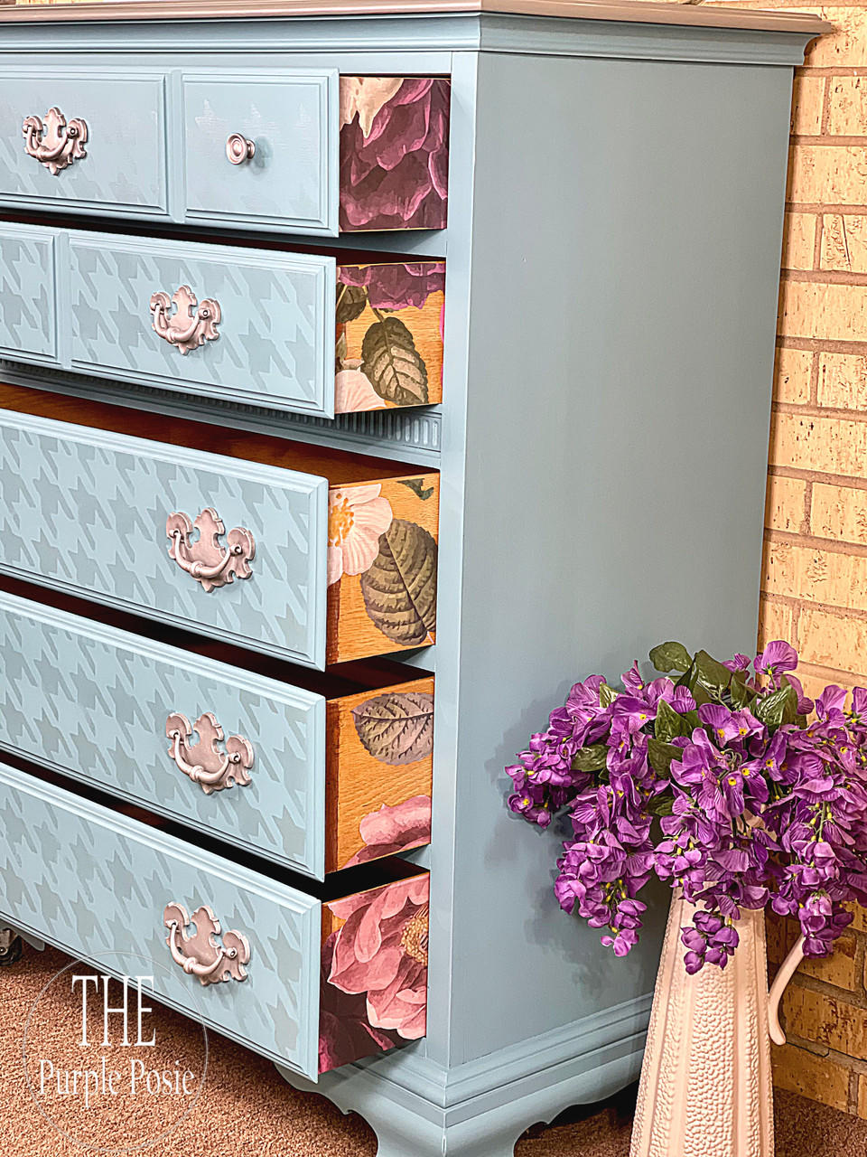Belles and Whistles Houndstooth - Stencil provides an extra decorative touch to any project!
A chest of dresser with the drawers opened, the drawers are decorated with Houndstooth - Stencil. The opened drawers are showing the sides using the Floral Romance Transfer. Staged next to a ceramic vase with purple flowers inside.