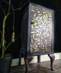 Belles and Whistles Leaf Me Alone - Stencil provides an extra decorative touch to any project! Purplish black cabinet makeover with the Leaf Me Alone stencil applied on the front of the cabinet in gold.
