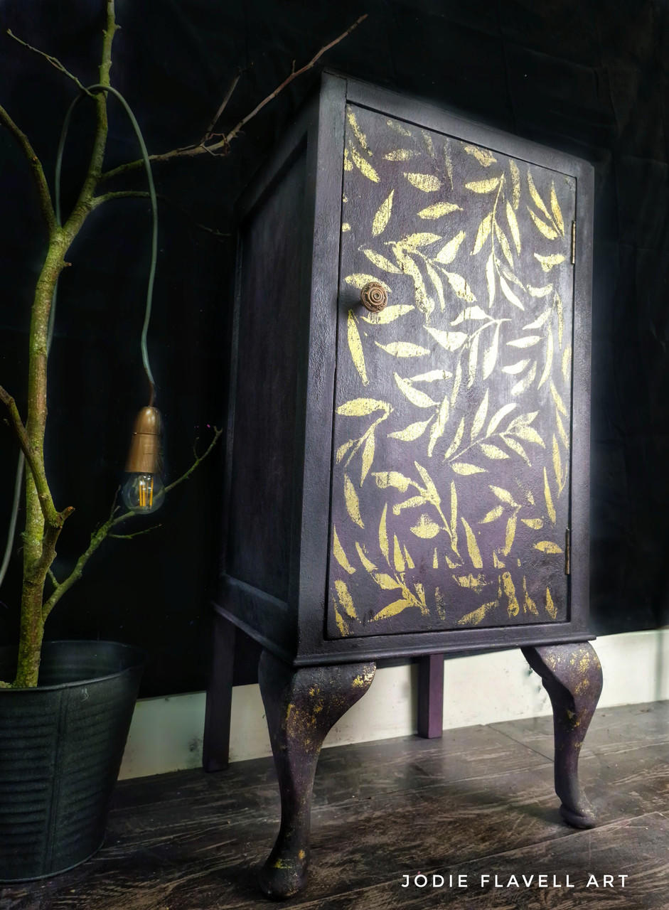 Belles and Whistles Leaf Me Alone - Stencil provides an extra decorative touch to any project! Purplish black cabinet makeover with the Leaf Me Alone stencil applied on the front of the cabinet in gold.