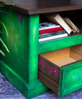 Belles and Whistles Lotus Bloom - Stencil provides an extra decorative touch to any project!
Green entertainment table with purple hardware. Displayed with one drawer open showing the outside of drawer lined with Lotus Bloom - Stencil in purple .