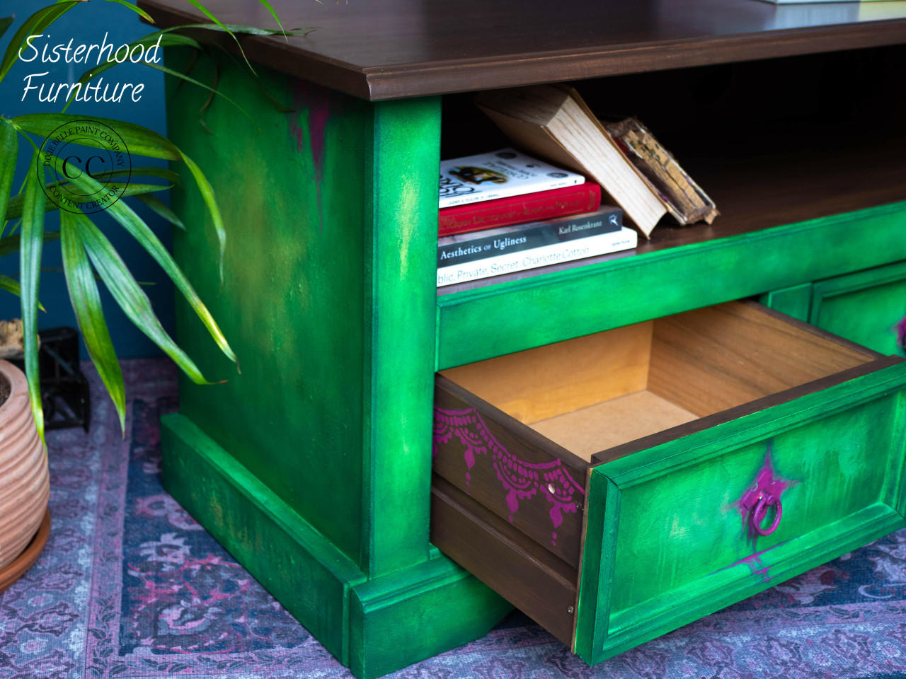 Belles and Whistles Lotus Bloom - Stencil provides an extra decorative touch to any project!
Green entertainment table with purple hardware. Displayed with one drawer open showing the outside of drawer lined with Lotus Bloom - Stencil in purple .