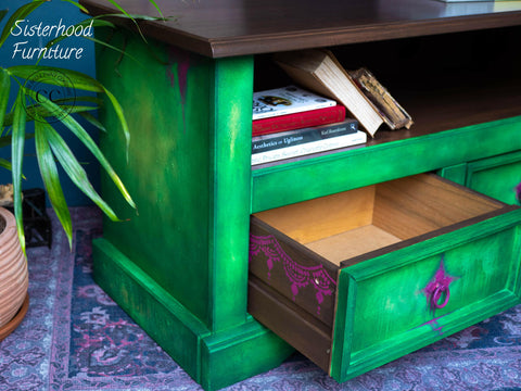 Belles and Whistles Lotus Bloom - Stencil provides an extra decorative touch to any project!
Green entertainment table with purple hardware. Displayed with one drawer open showing the outside of drawer lined with Lotus Bloom - Stencil in purple .