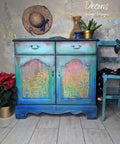Belles and Whistles Morocco - Stencil provides an extra decorative touch to any project!
Blue distressed Ombre chalk painted cabinet  with a rainbow painted Morocco stencil on the doors. Staged with plants and a hat on the wall.