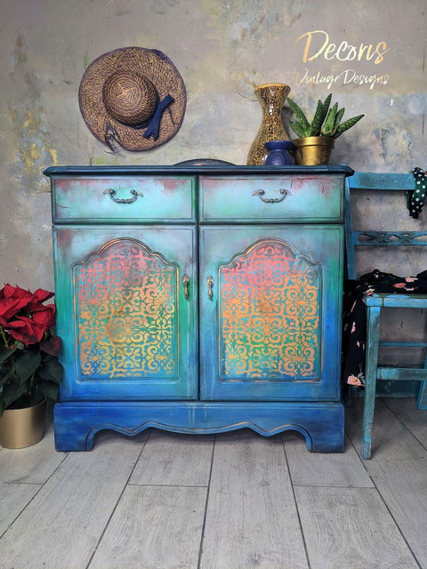 Belles and Whistles Morocco - Stencil provides an extra decorative touch to any project!
Blue distressed Ombre chalk painted cabinet  with a rainbow painted Morocco stencil on the doors. Staged with plants and a hat on the wall.
