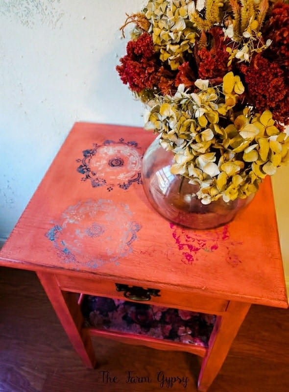 Belles and Whistles Mosaic - Silkscreen Stencil provides an extra decorative touch to any project! Red end table painted with Belles and Whistles Mosaic Silkscreen Stencil on top. Staged with Florals and glass vase.