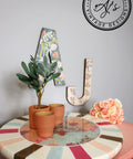 Belles and Whistles Native Rose - A1 Rice Decoupage Paper is a simple way to visually enhance any surface of your project! Colorful striped circle stand with native rose decoupage in the middle and staged with clay pots and a small plant.