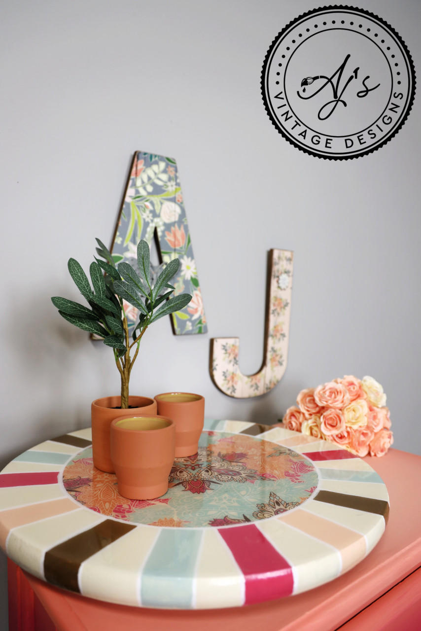 Belles and Whistles Native Rose - A1 Rice Decoupage Paper is a simple way to visually enhance any surface of your project! Colorful striped circle stand with native rose decoupage in the middle and staged with clay pots and a small plant.