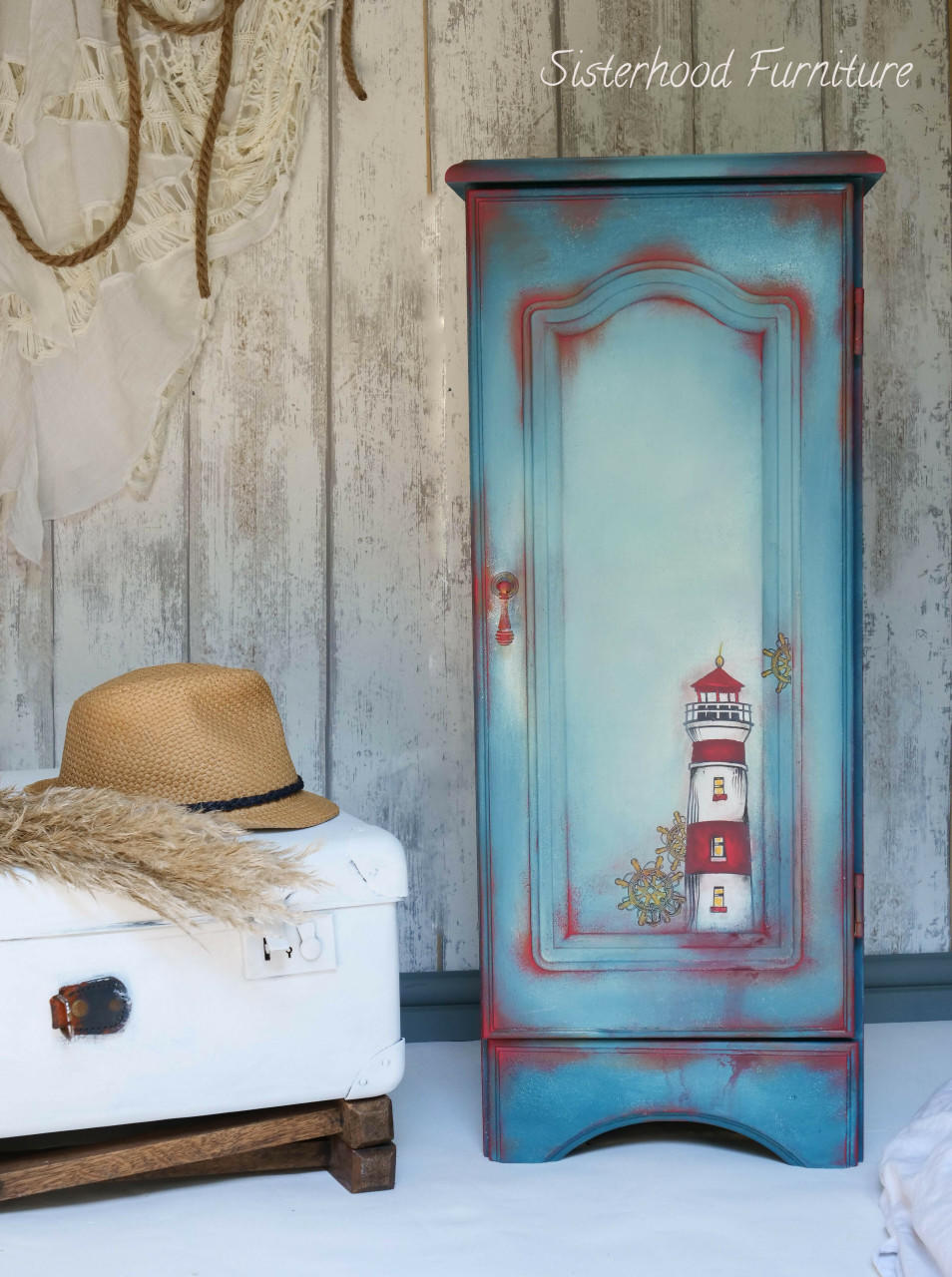 Belles and Whistles Nautical - Silkscreen Stencil provides an extra decorative touch to any project! Blue and red chalk painted armoire with a light house and ship wheel stenciled on. Staged next to a white luggage.