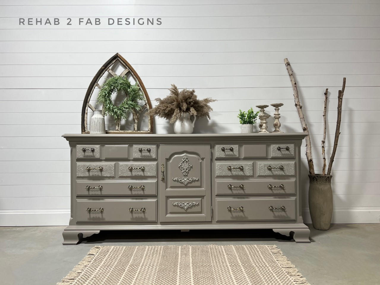 Large gray painted dresser staged in front of a white panel wall. The Royal Damask stencil has been applied in white on the front of some of the drawers.
