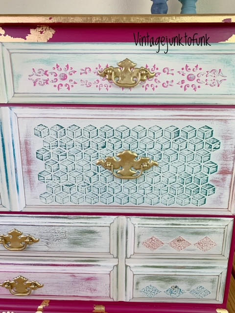 Belles and Whistles Trippy Blocks - Stencil.  The right side of a pink, blue and white dresser.  the handles are painted gold, and there is gold trim and gold spots on the dresser.  The drawers are blue and pink with white chalk paint dry brushed over the stenciled patterns.