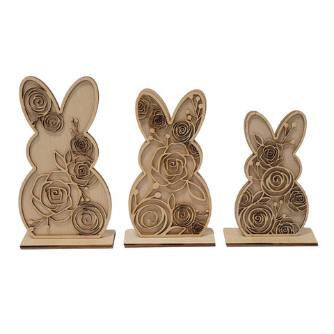 Three wooden bunny sculptures with intricate floral engravings. The rabbits vary in size, with the largest on the left and smallest on the right, each featuring detailed rose designs.