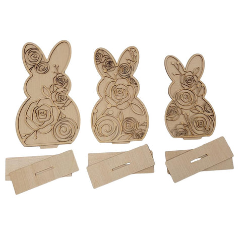 Three wooden bunny-shaped cutouts with floral cutout patterns, each accompanied by a rectangular stand. The intricate designs feature roses and other flowers, adding a decorative touch to the standing bunnies.